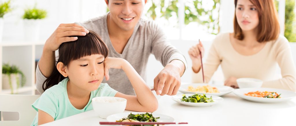 parent coaxing child to eat vegetables child not happy